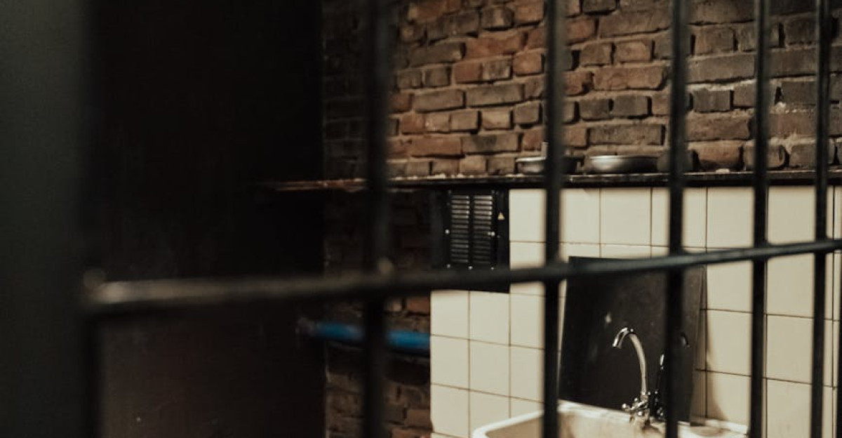 Atmospheric view of a jail cell with wooden bed sink and dumbbells