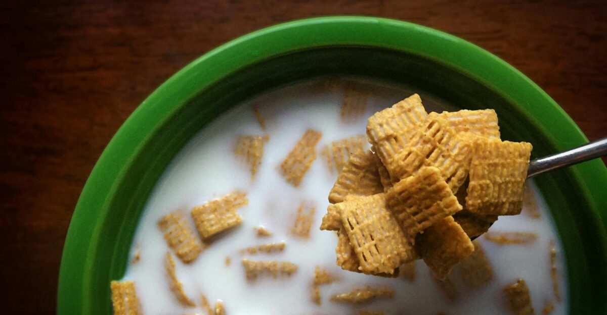 Top view of Chex cereal in milk inside a green bowl showcasing a spoonful of cereal