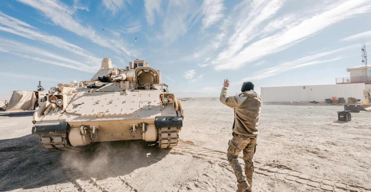 Bradley Fighting Vehicle and soldier in desert training operation under clear sky