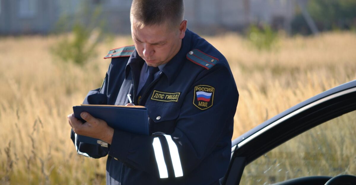 Police officer in uniform taking notes beside a car in a field