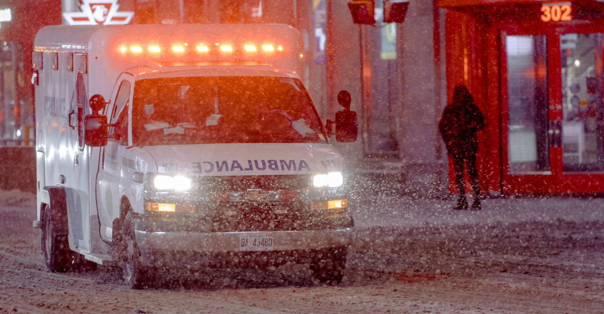 Ambulance on a snowy street during a winter emergency response at night.