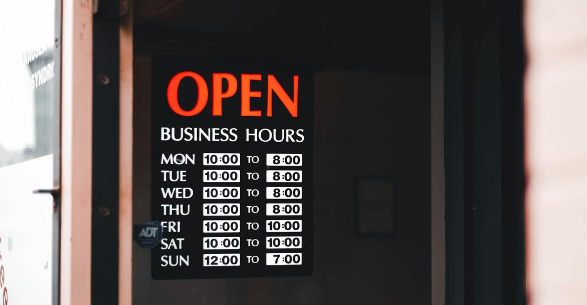 Close-up of an open business hours sign displayed in a shop window