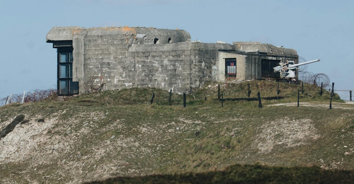 Abandoned WWII concrete bunker on a grassy hill under a clear blue sky