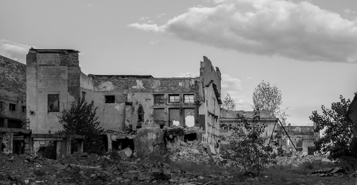 A woman walks through the ruins of Donetsk, Ukraine, symbolizing resilience amidst destruction.