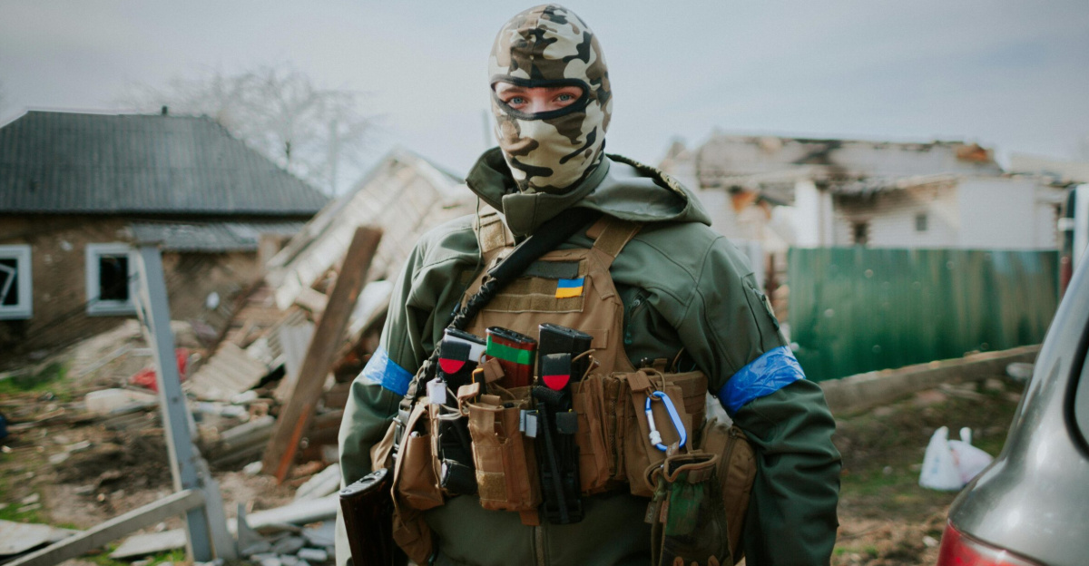 Soldier in camouflage gear standing in Kyiv Oblast, Ukraine amidst destruction.