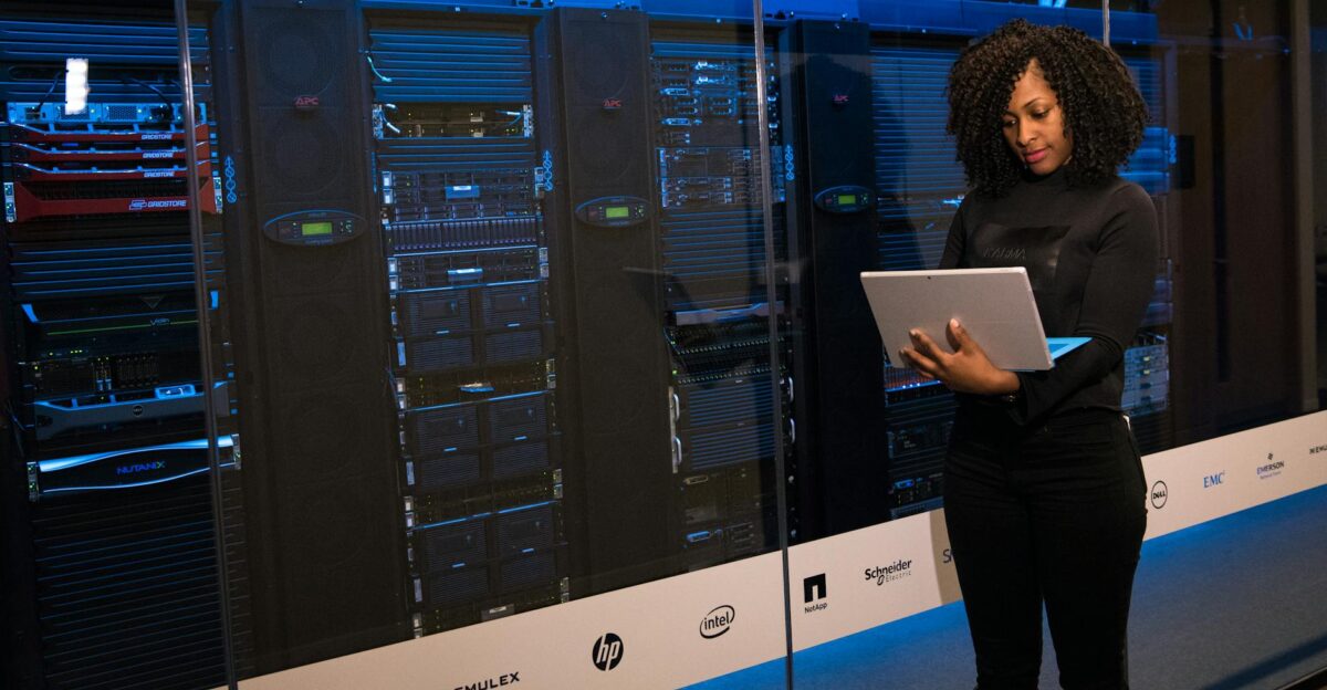 A female engineer using a laptop while monitoring data servers in a modern server room