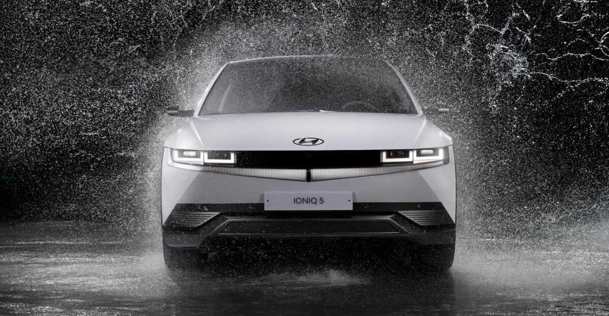 Dynamic front view of a Hyundai Ioniq 5 splashing through rain captured in black and white