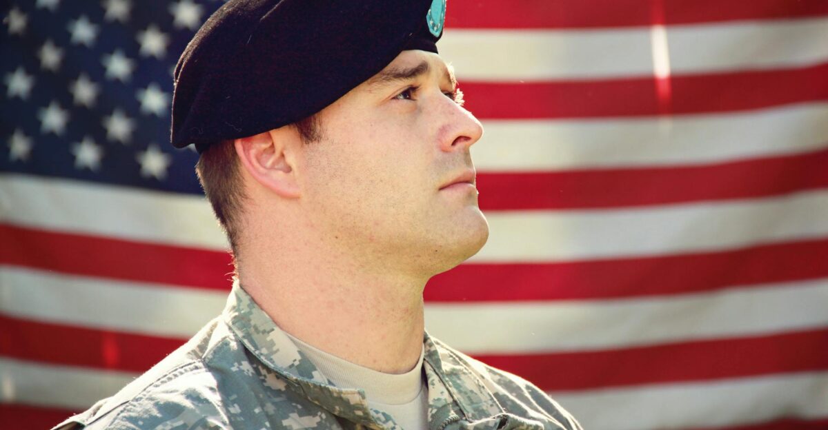 US soldier in uniform stands proudly with the American flag in the background capturing a sense of patriotism