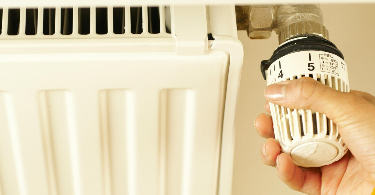 Close-up of hand adjusting radiator thermostat to control home heating temperature.