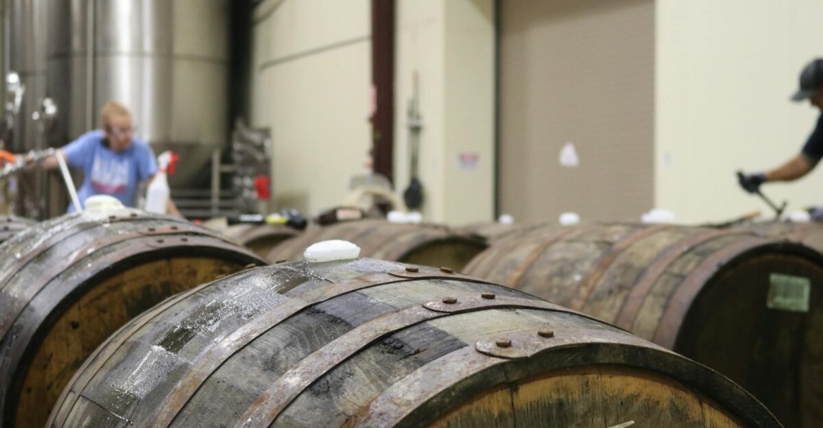 A distillery interior featuring wooden barrels Workers are busy in the background showcasing the production process
