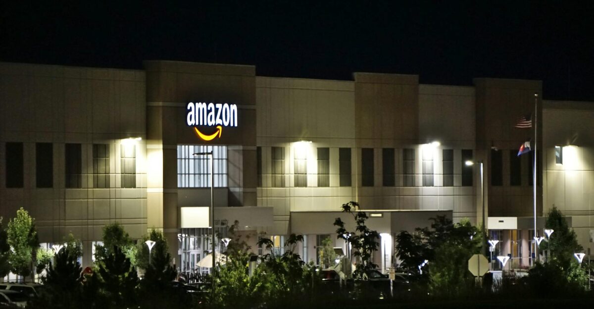 Amazon warehouse building illuminated at night with trees and signage