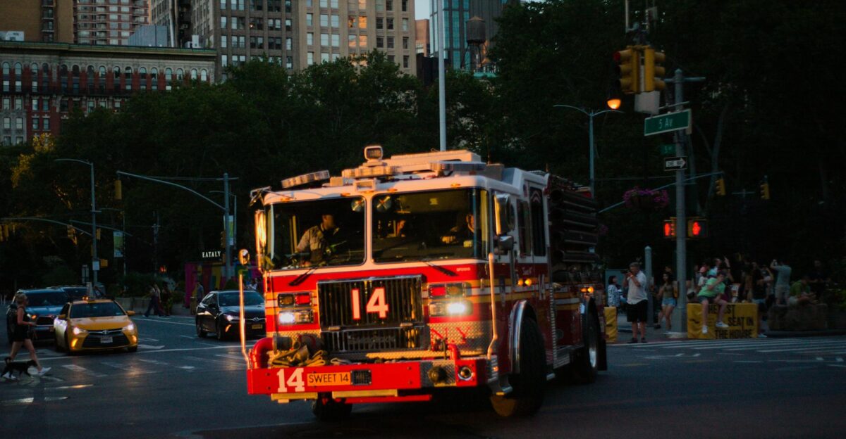 A firetruck navigates New York City s streets at dusk surrounded by urban life