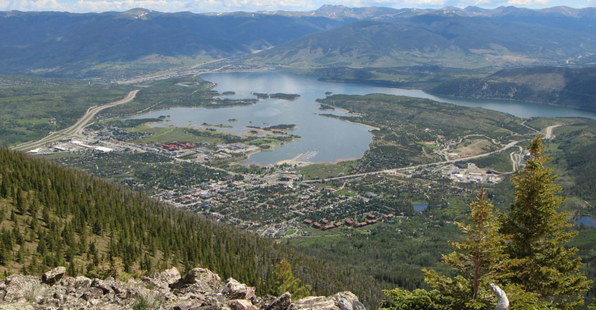 Stunning aerial view of Frisco, Colorado with lake and mountains under a cloudy sky.