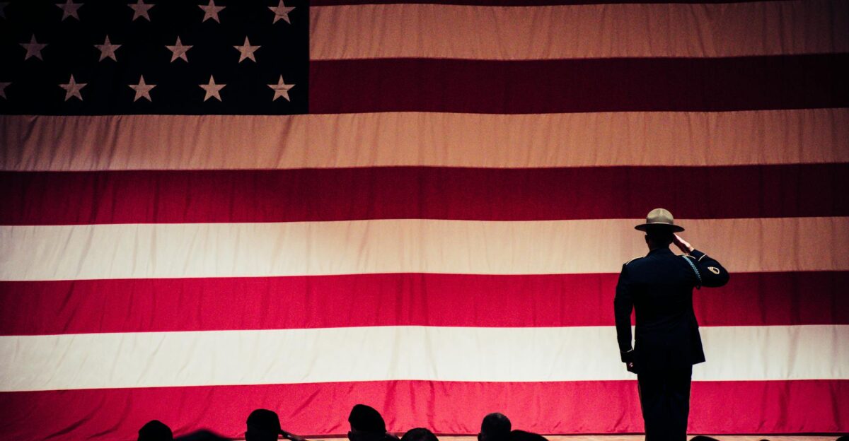 A solemn moment as a soldier salutes the American flag during a ceremony inside an auditorium