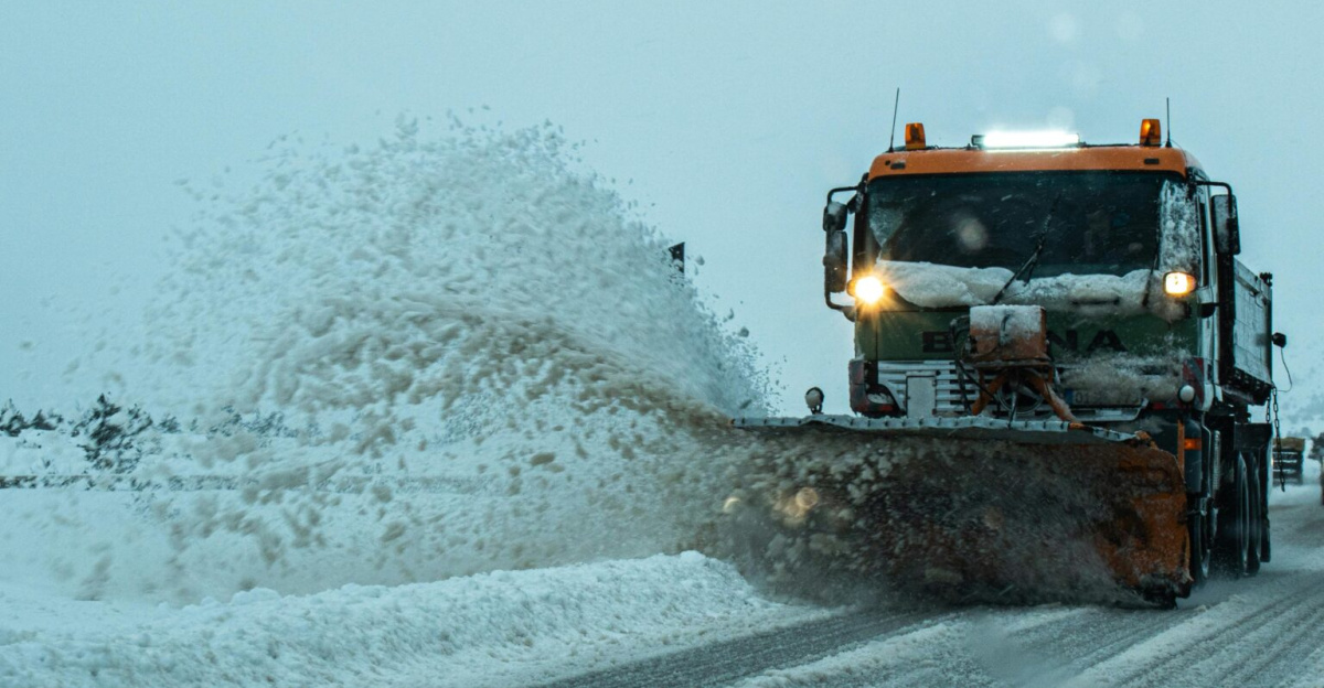 A snow plow clears a snow-covered road during winter, ensuring safe transportation for vehicles.
