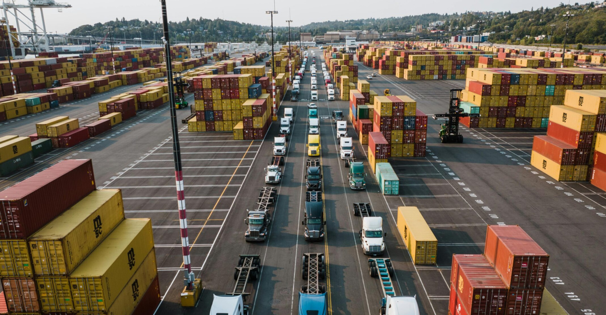 A bustling aerial shot of Seattle's shipping port with trucks lined up amongst colorful cargo containers.
