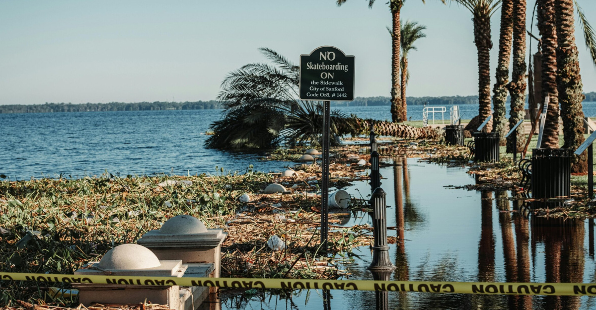 A flooded pathway with caution tape and palm trees by a lake in Sanford, Florida.