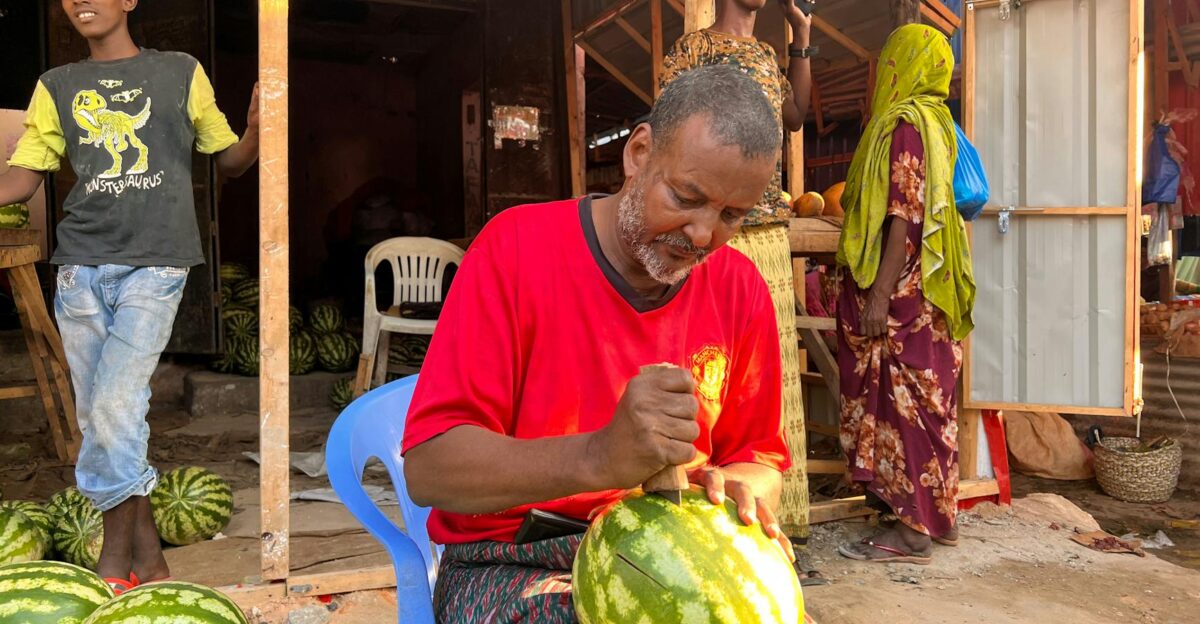A vendor skillfully slices watermelon at an outdoor market in Mogadishu Somalia