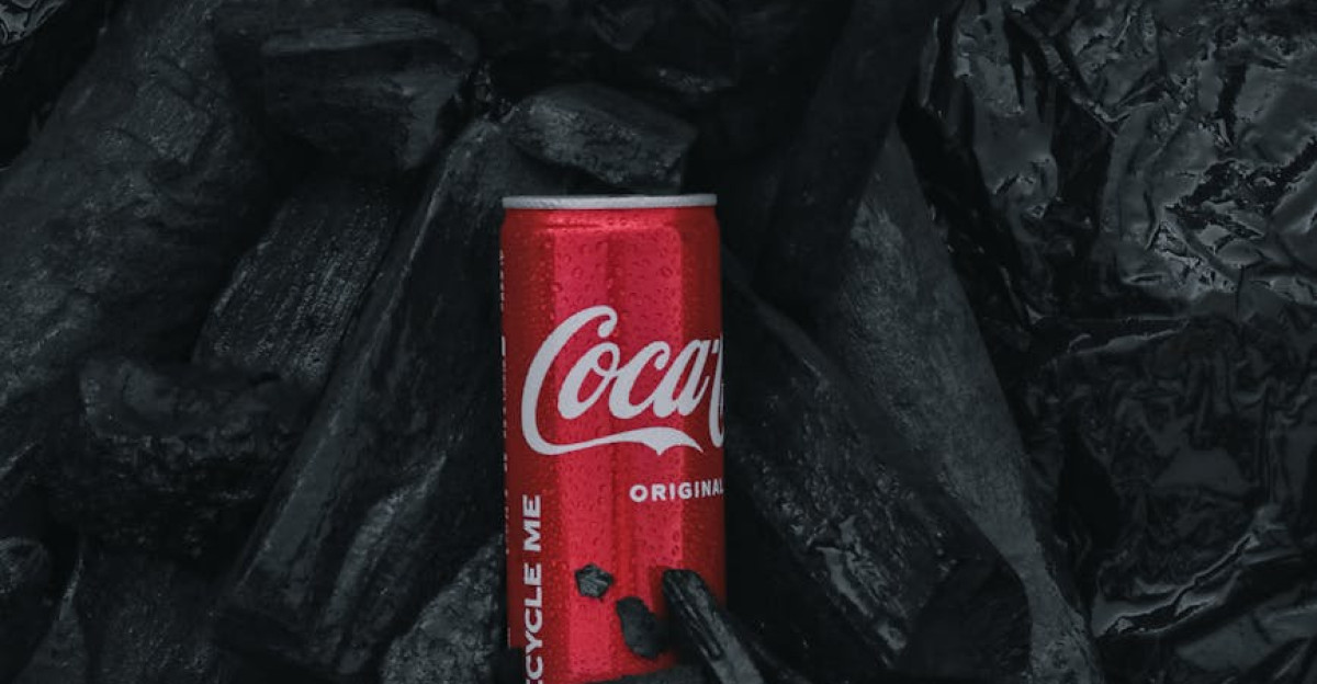 A Coca-Cola can placed amidst dark black charcoal rocks for a striking contrast
