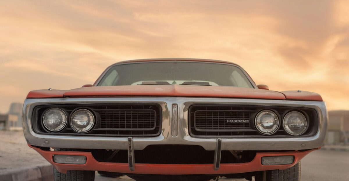 Front view of a classic Dodge muscle car under a vibrant sunset in Sharjah UAE