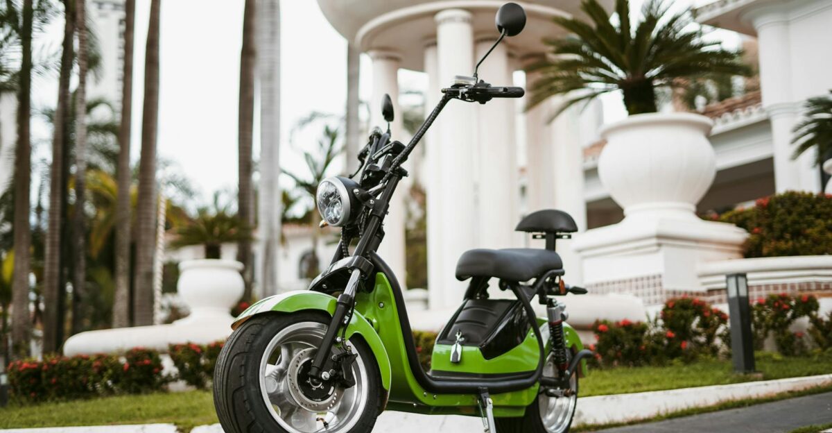 A stylish green electric moped parked in an outdoor urban setting during the day