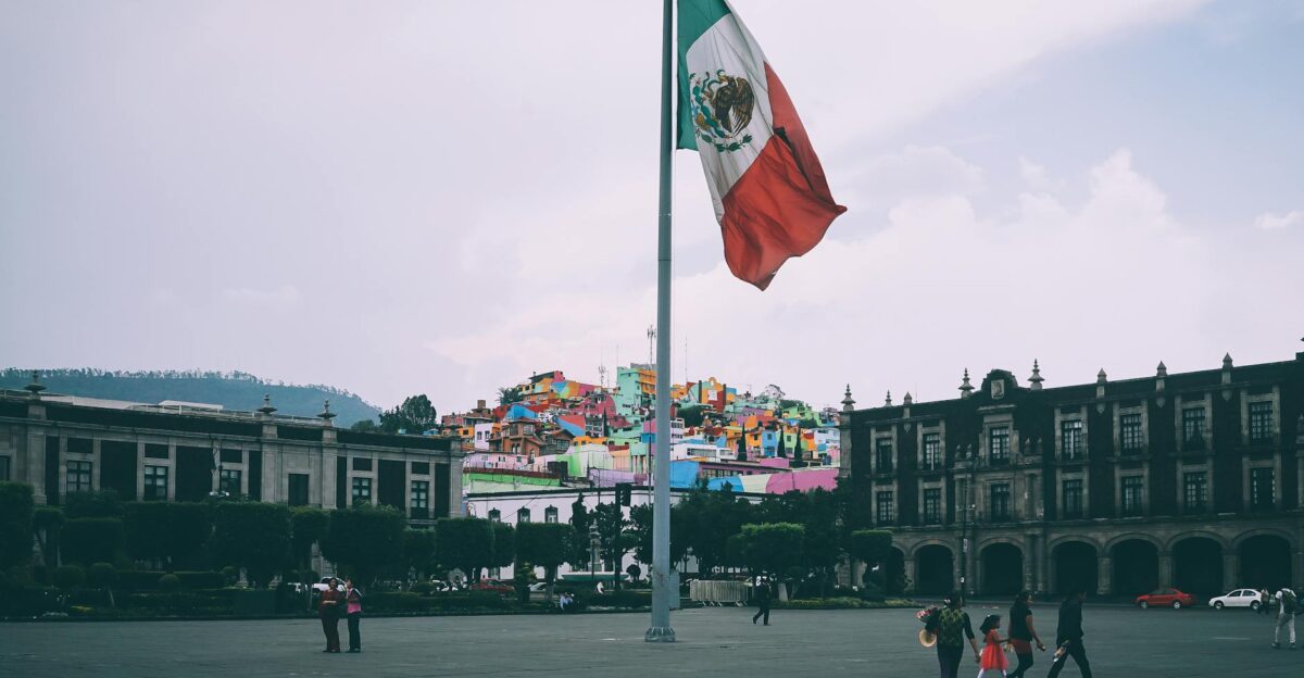 Colorful cityscape of Toluca with large Mexican flag in the foreground vibrant buildings in the backdrop