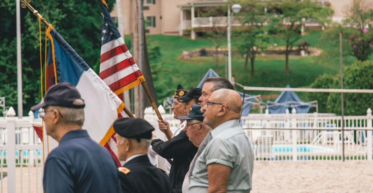 Group of veterans holding flags during an outdoor ceremony showing patriotism