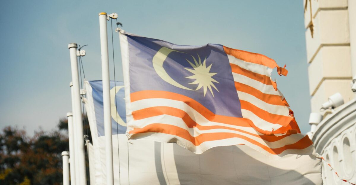 A vibrant Malaysian flag waving against a clear blue sky symbolizes national pride and patriotism
