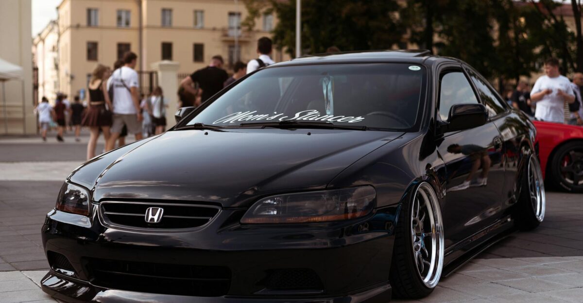 Black Honda Accord showcased in a lively town setting with people in the background