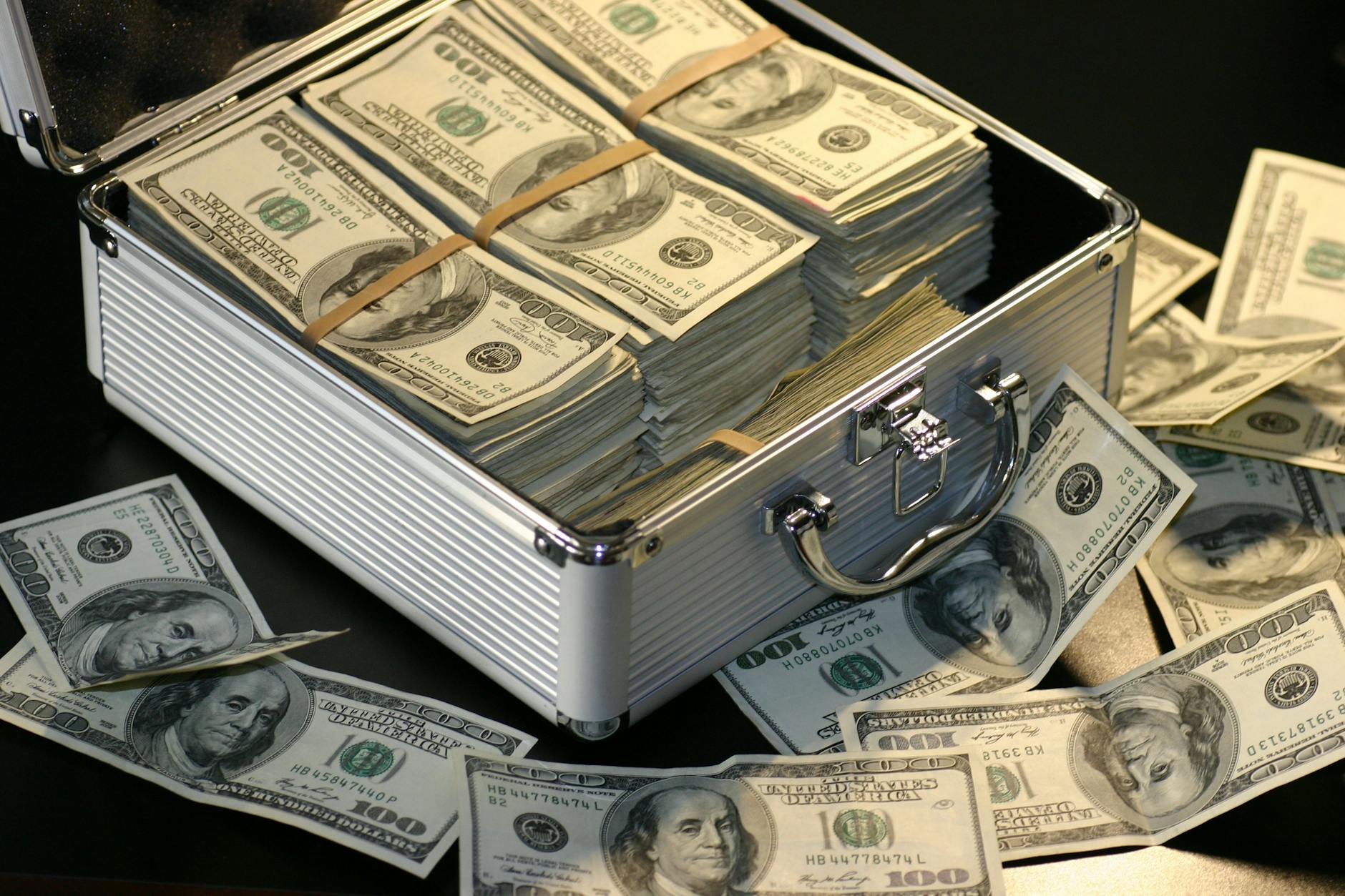 A metallic briefcase full of US dollar bills symbolizing wealth and investment