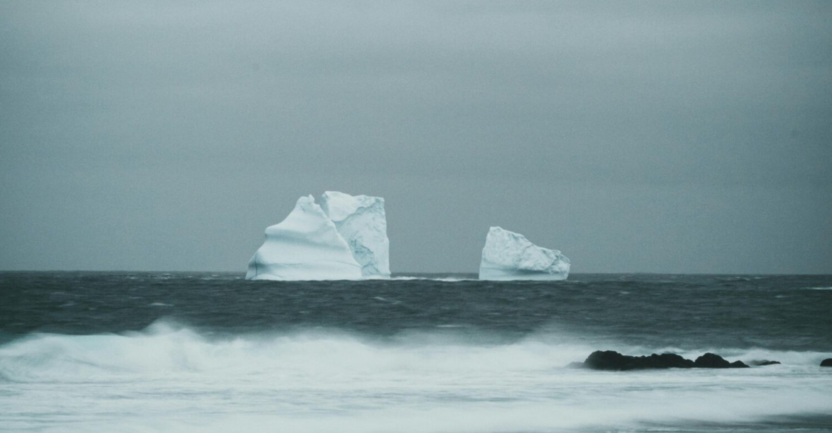 Majestic icebergs float in a turbulent sea under a cloudy sky, highlighting nature's raw beauty.