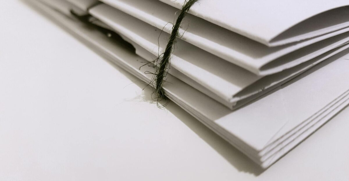 Pile of white envelopes tied with a green string showcasing a minimalist design