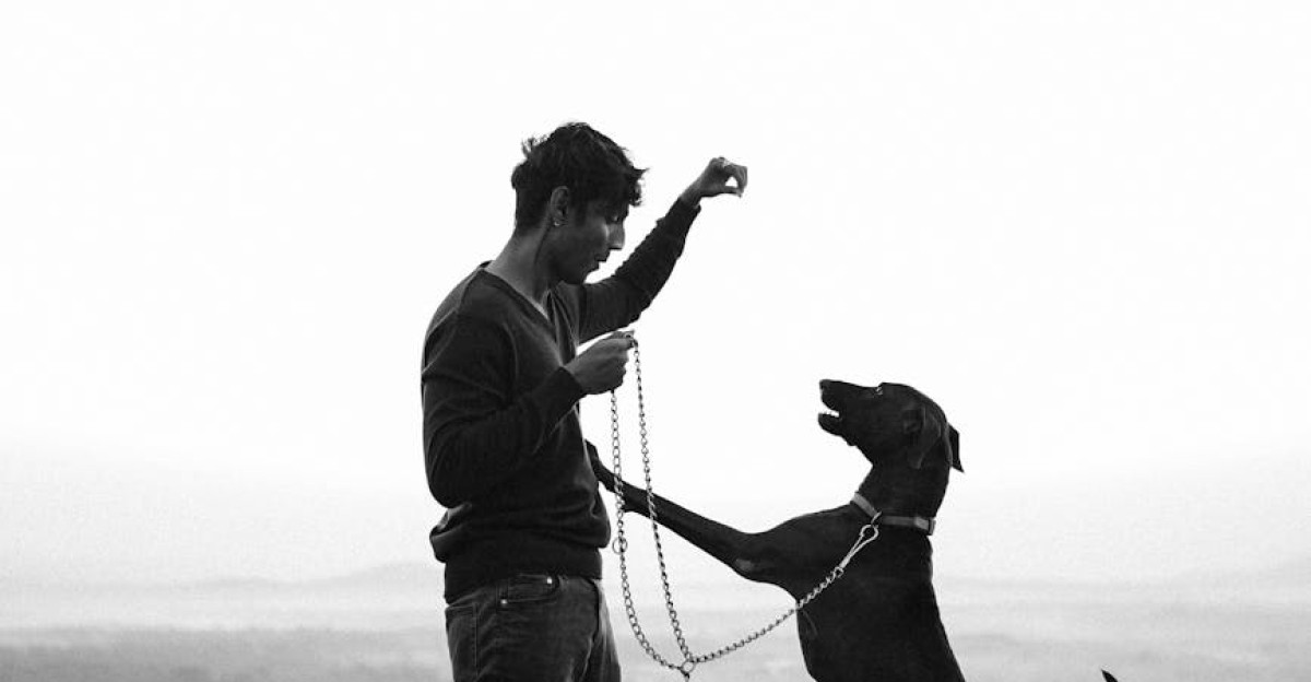 Black and white image of a man playing with his dog in rural Khanapur India
