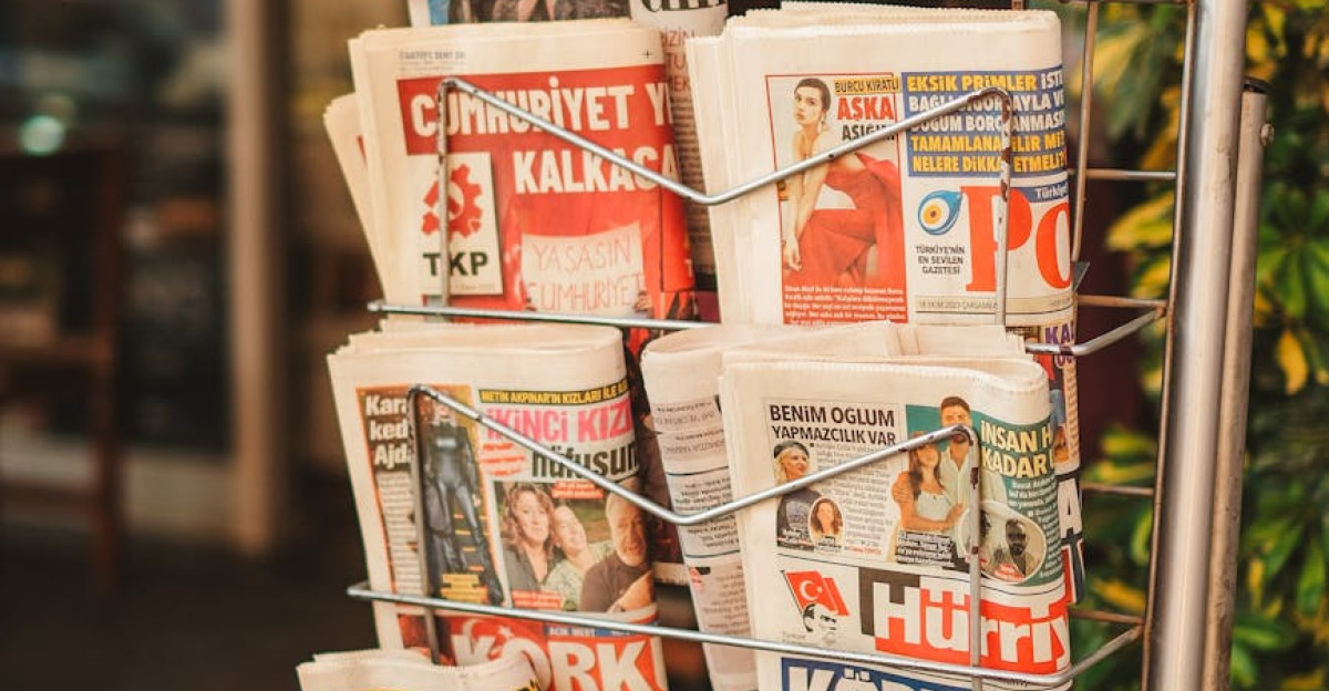 Stack of diverse newspapers in a metal stand showcasing media variety