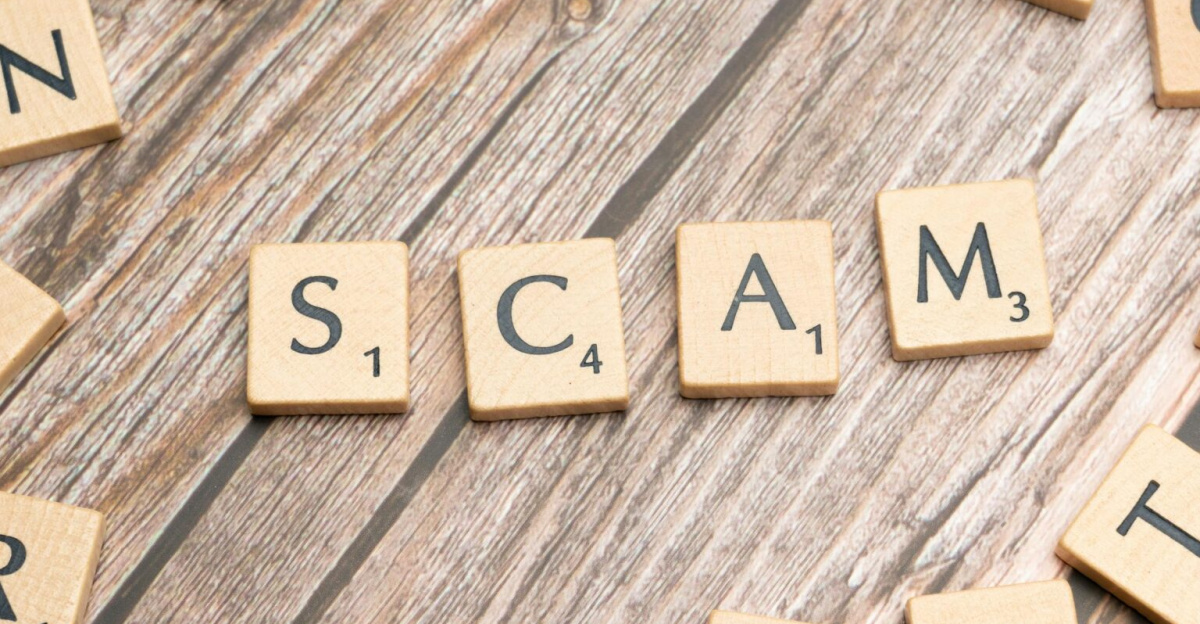 Scrabble tiles on a wooden background spell out the word 'scam', concept for deception and trickery.