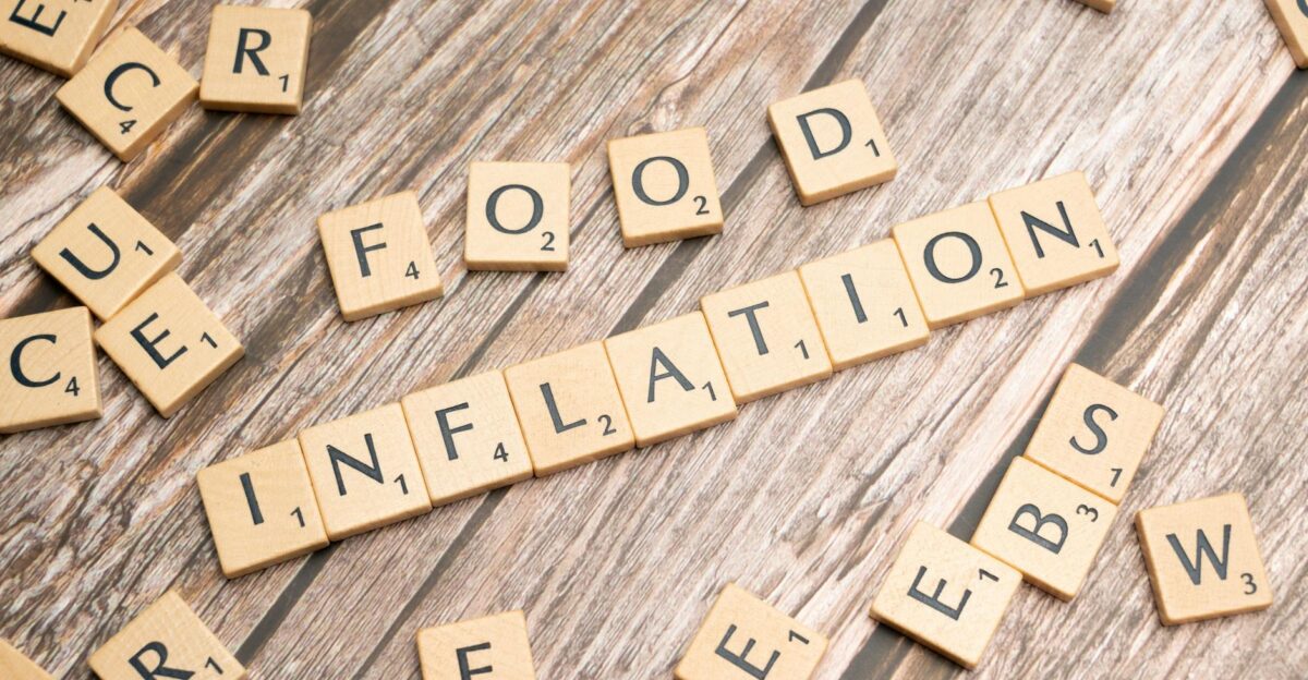 Wooden scrabble tiles arrange to spell Food Inflation on a rustic wooden surface conceptually depicting rising food prices