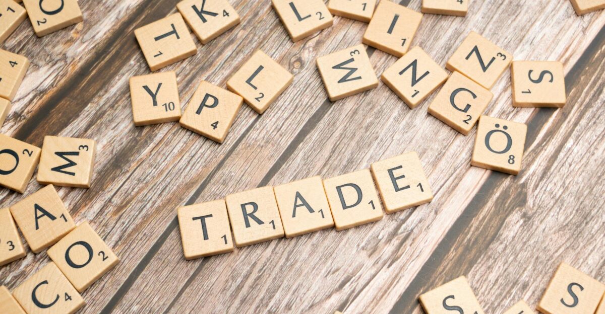 Scrabble letter tiles spelling trade on a wooden surface illustrating business concepts