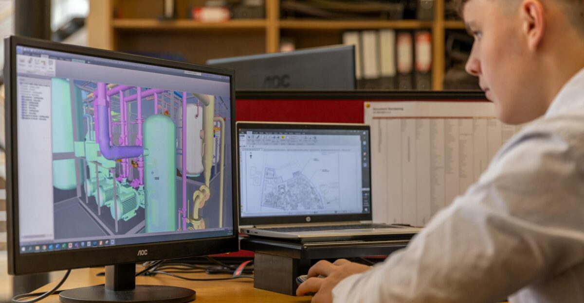 Engineer working with CAD software on dual monitors in an office setting