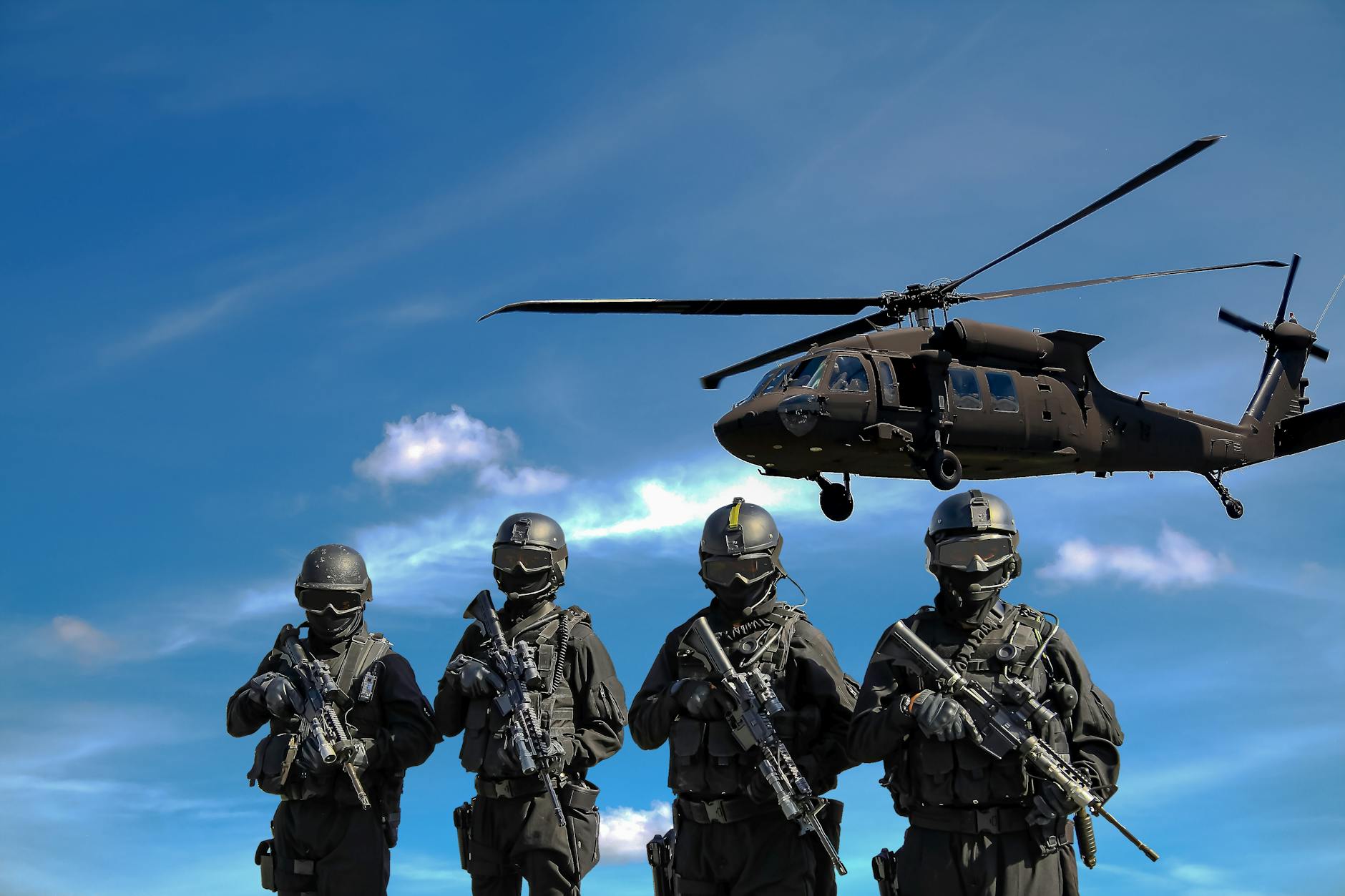 Special forces soldiers in tactical gear with helicopter overhead under a blue sky
