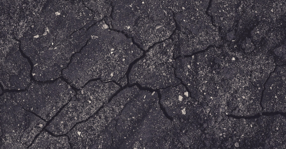 Close-up of cracked earth with dark tones, showcasing natural textures and patterns.