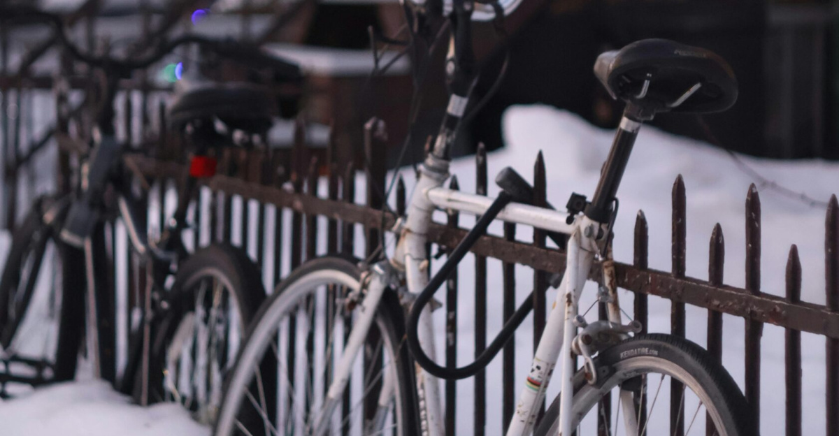 Bicycles covered in snow against a fence in Montreal during winter, creating a serene urban scene.