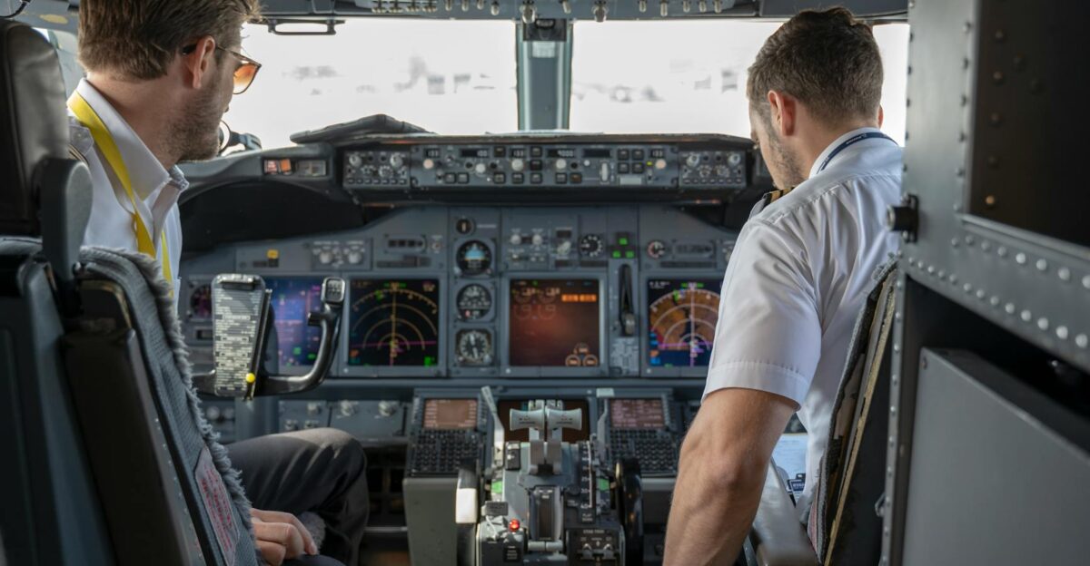 Two pilots navigating an aircraft cockpit focused on advanced avionics and flight systems