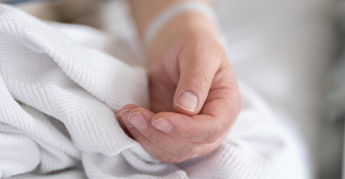 Detailed image of an adult patient's hand resting on a hospital bed with IV line, symbolizing healthcare and recovery.