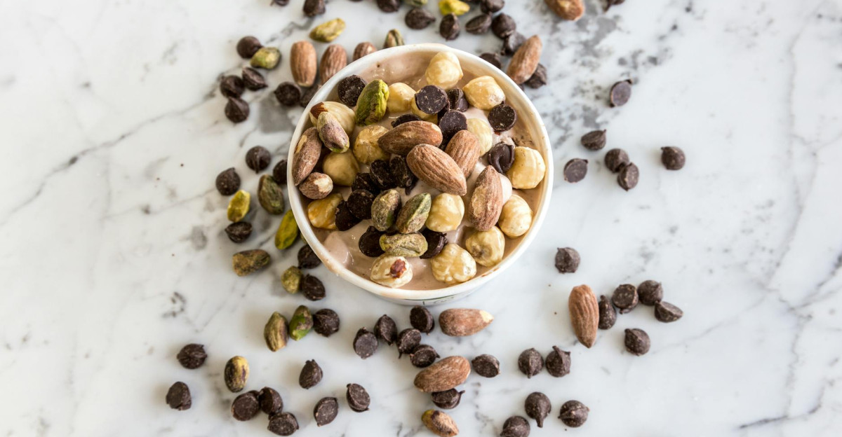 A bowl of mixed nuts and chocolate chips on a marble surface perfect for healthy snacking