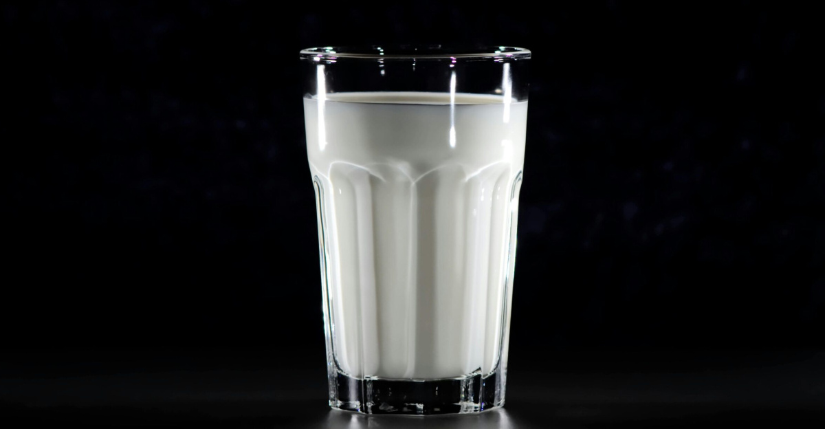 A glass of fresh milk against a black background, emphasizing simplicity and nutrition.