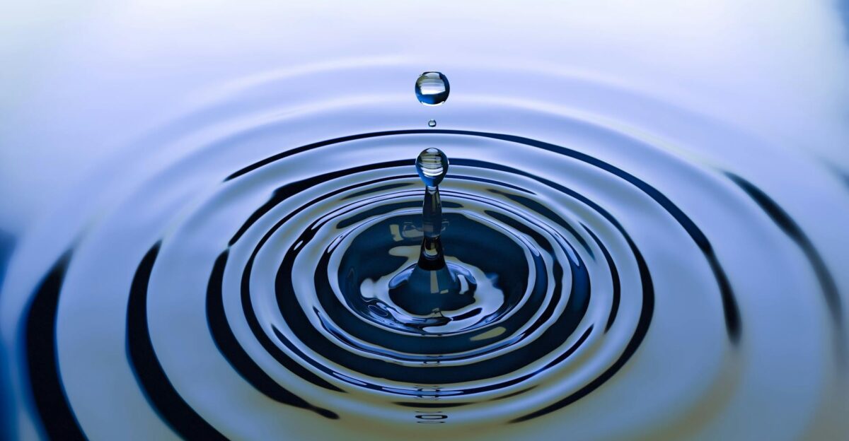 A stunning close-up of a water droplet creating ripples on a smooth water surface capturing nature s simplicity
