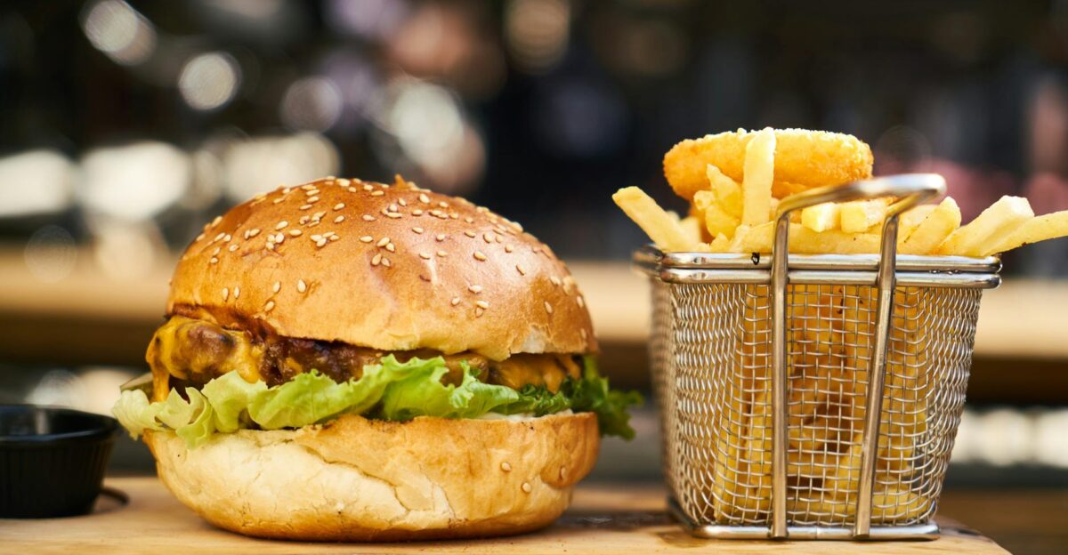 A delicious cheeseburger with crispy french fries served on a wooden platter perfect for lunch or dinner