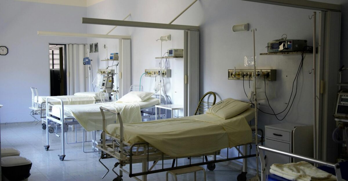 Spacious hospital room with several empty beds and medical equipment emphasizing healthcare and hygiene