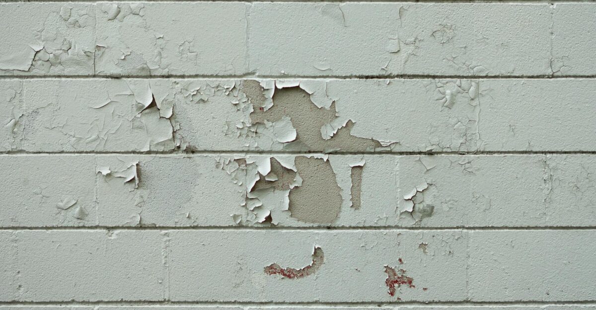 Close-up of an old brick wall with peeling white paint showcasing urban decay and texture