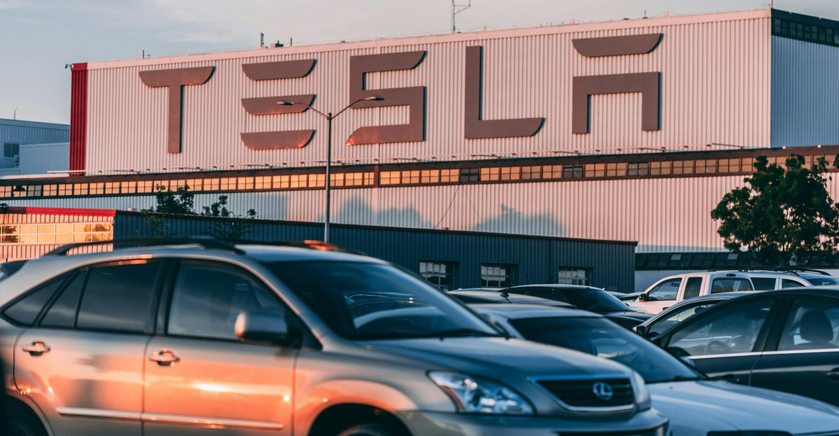 Tesla factory with parked cars during sunset, showcasing modern automotive industry vibes.